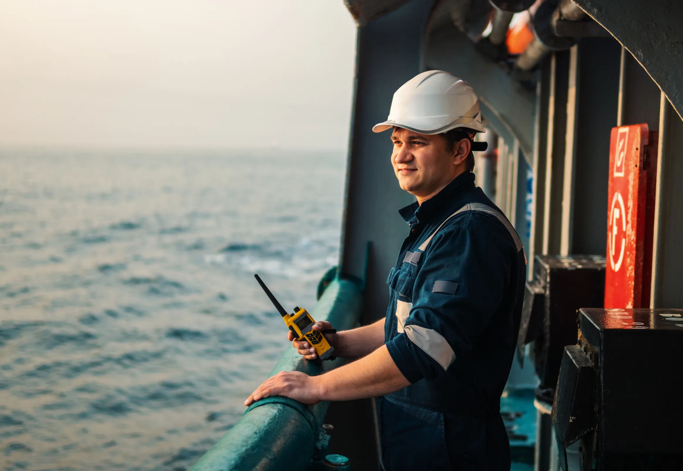 An oil rig operator looking out over a railing at the ocean